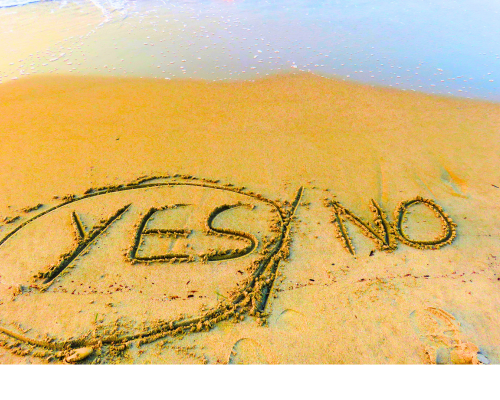 Photo of words "Yes" and "No" scratched into sand with "Yes" circled