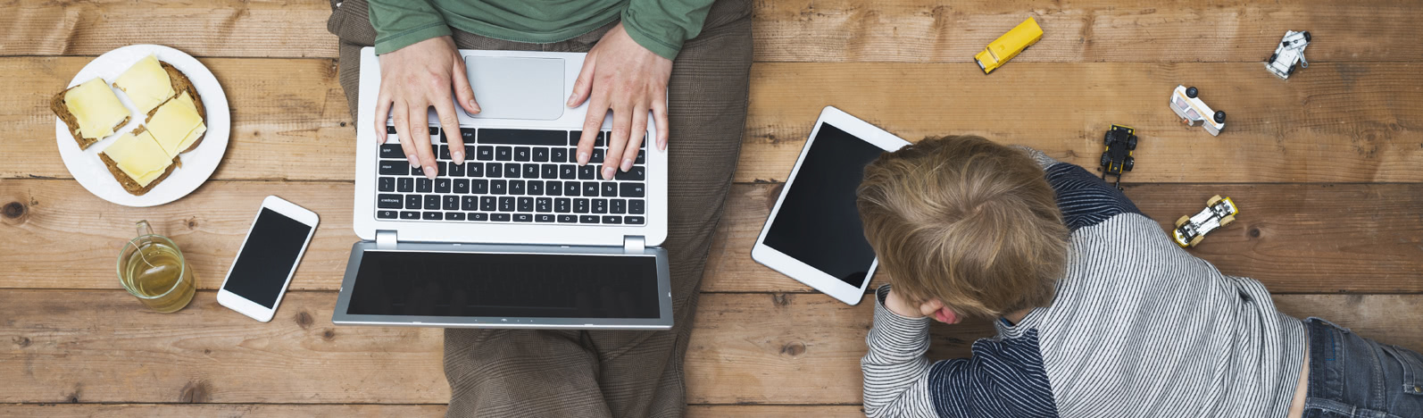 Adult student on a laptop works along side a child.