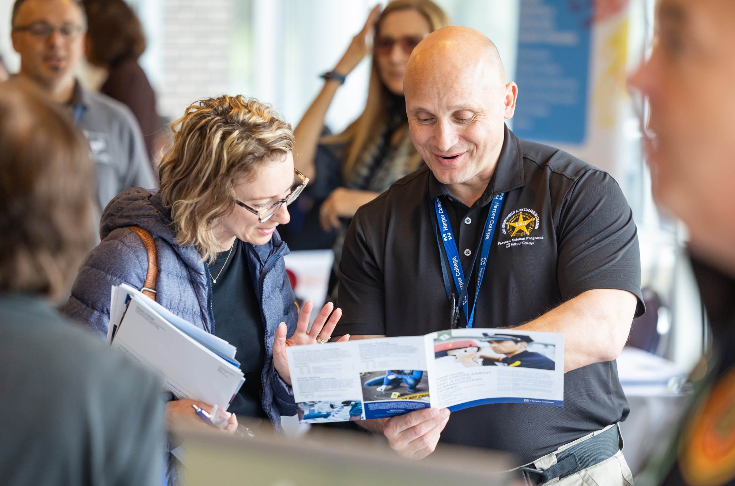 A member of Harper College's Law Enforcement and Justice Administration staff helping a student look over a brochure for the program