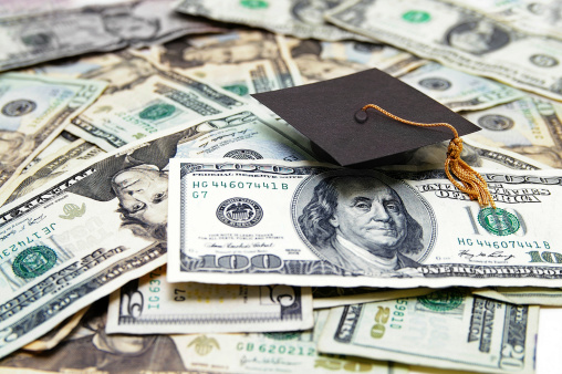 Pile of money with a graduation cap on top. 