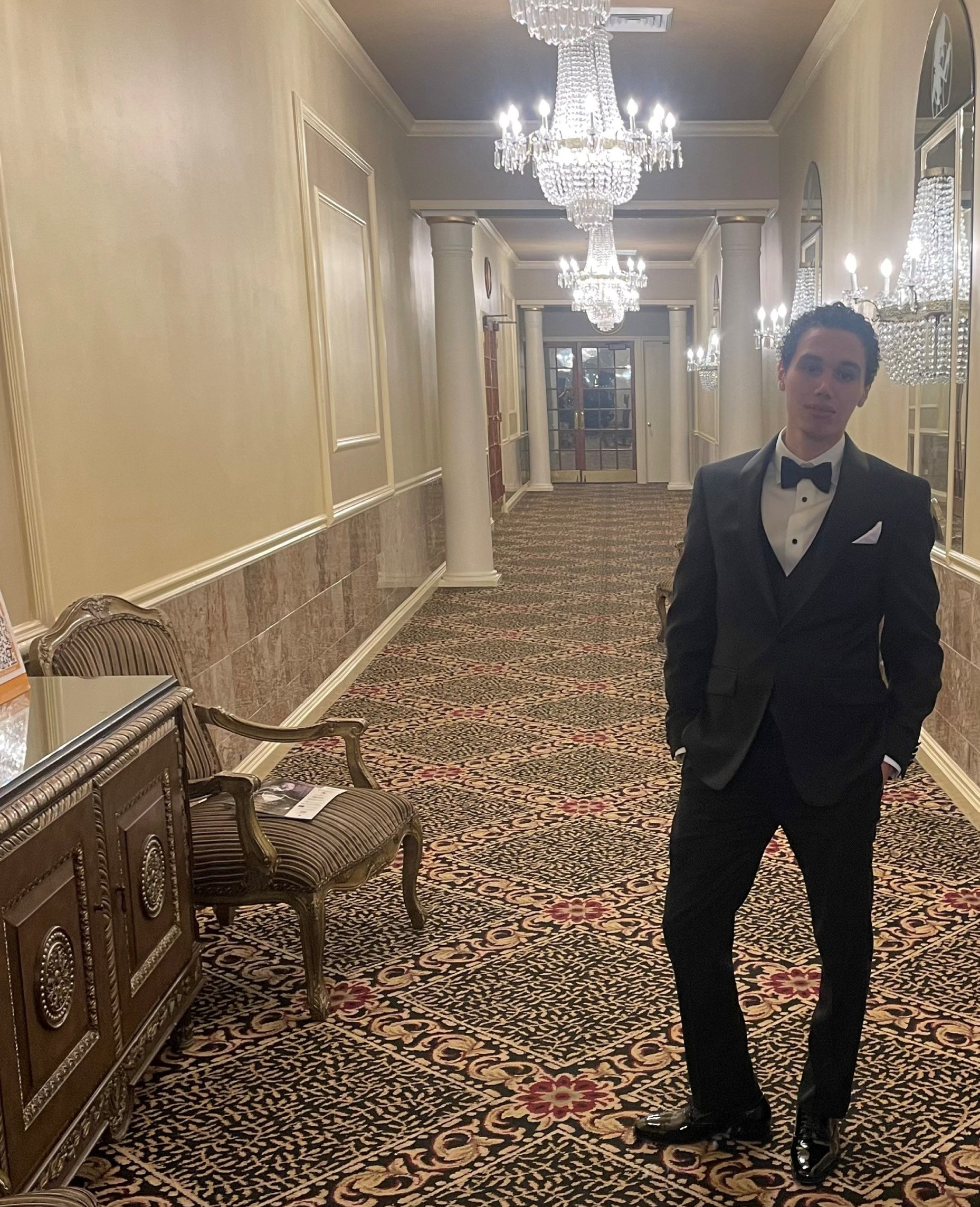 Ibrahim Wehbi wearing a suit in a hallway lined with chandaliers