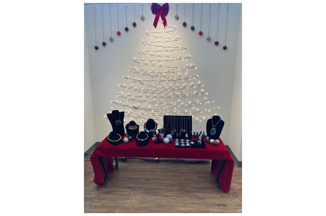 handmade jewelry on red display table with Christmas tree in lights in background