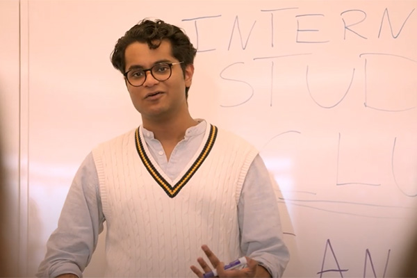 Dayaan presents in front of a white board.