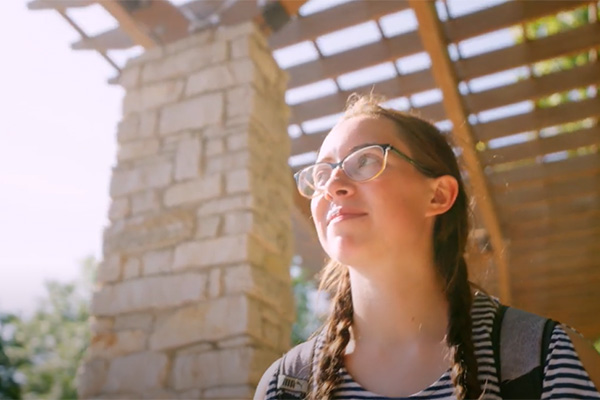 Kristin walks below the pergola on campus