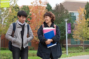 Student walking through campus, holding books