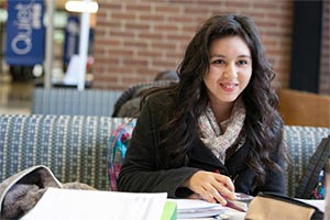 Student smiling, sitting at a table