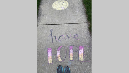 Photo of shoes standing by chalk art that says, "Have Hope."